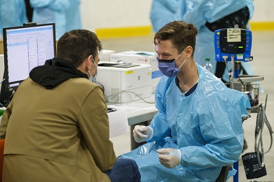 A person in a jacket sitting talking to a person sitting in protective gear