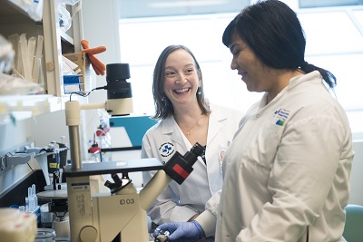 two people in lab coats working on a microscope