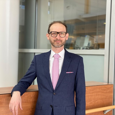 une personne en costume et une cravate debout devant un mur de verre