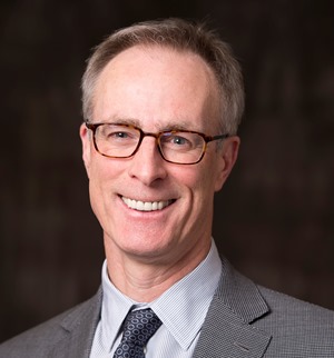 une personne en costume et cravate souriant