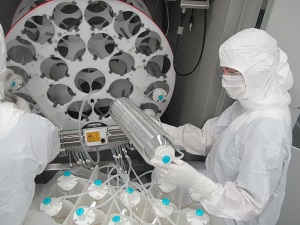two people in white suits and white gloves are working on a large machine