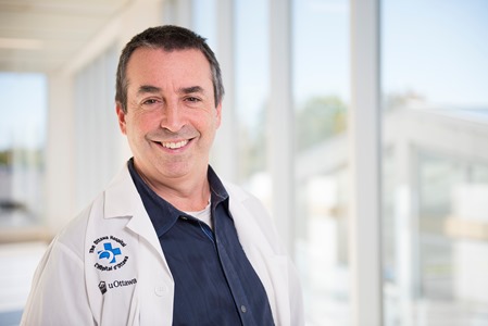 a person in a white lab coat standing in front of a window
