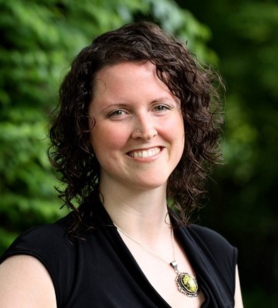 a person in a black dress standing in front of trees