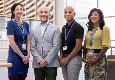 four people standing in a room with a large window