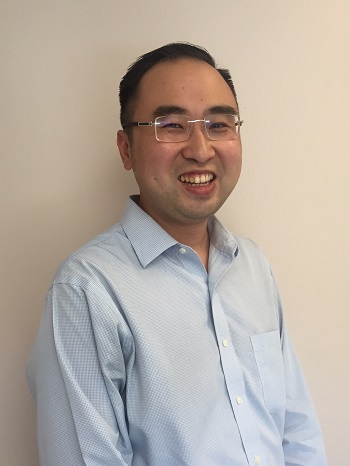 a person in a blue shirt and glasses standing against a wall