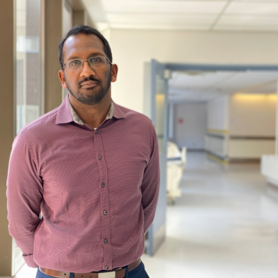 a person in a pink shirt and glasses standing in a hallway