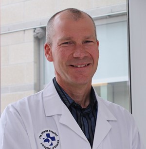 a person in a white lab coat standing in front of a window