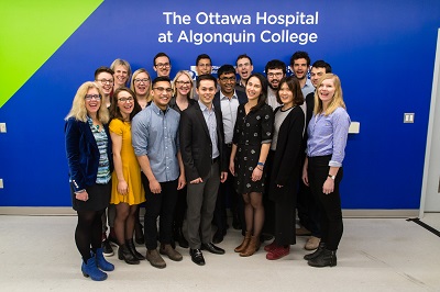 Group of people posing for a picture in front of a blue wall with message 