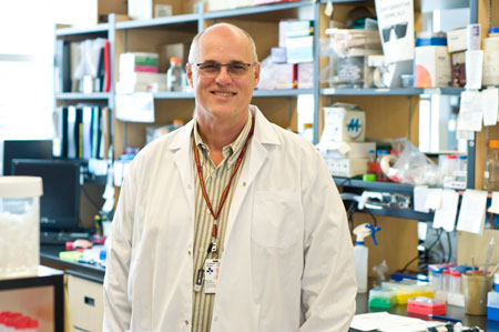 a person in a lab coat standing in front of a desk