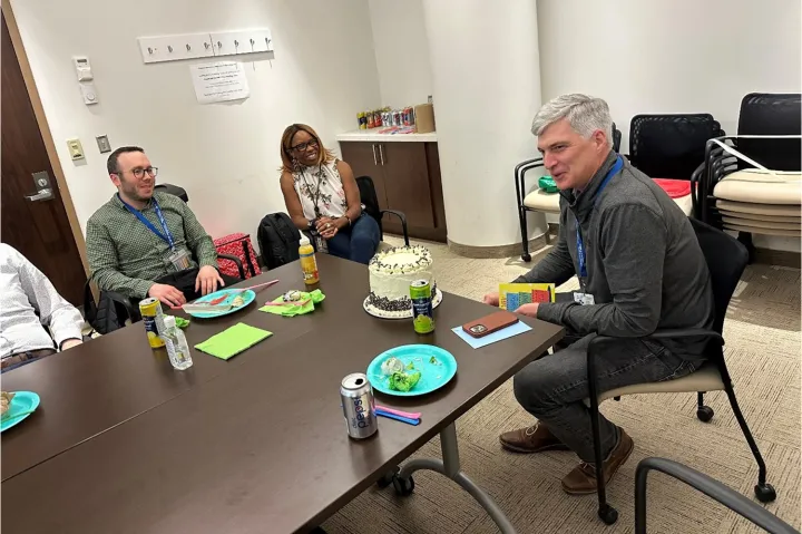 Members of the Blueprint team around a table, on which is a birthday cake