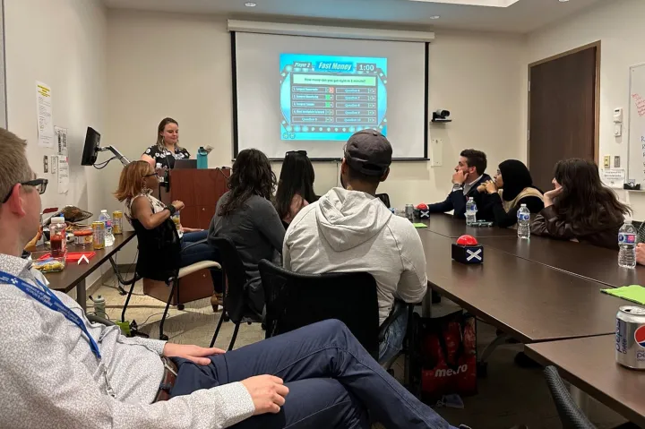 Members of the blueprint team sated around a table looking at a screen in the background showing the Family Feud game