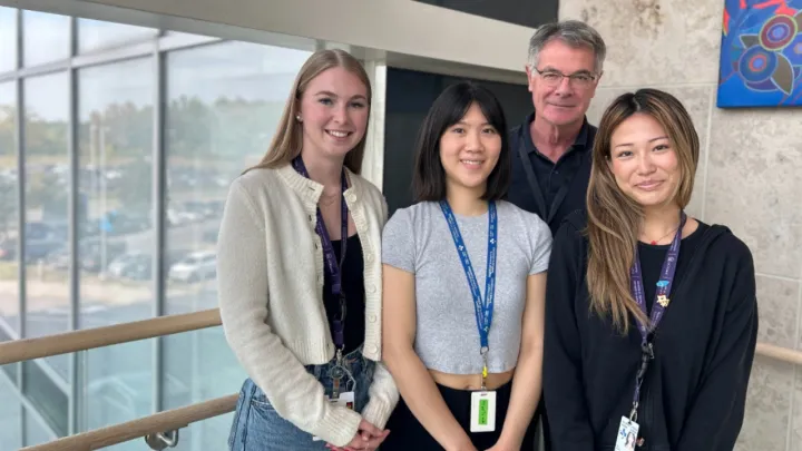 Four people stand and smile