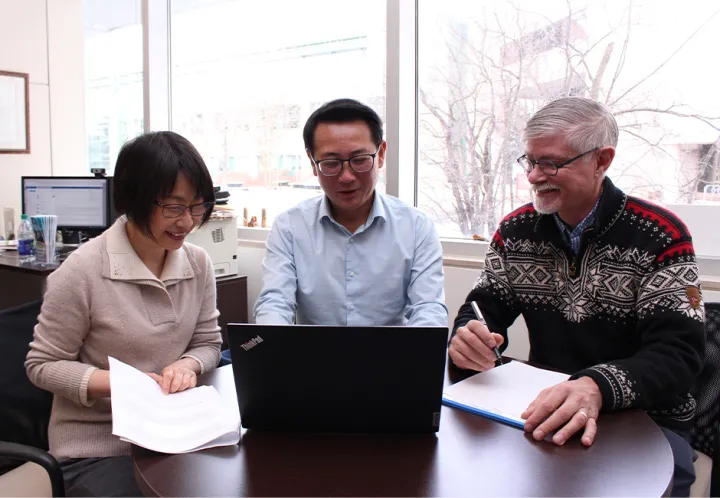 Three people look at a computer screen