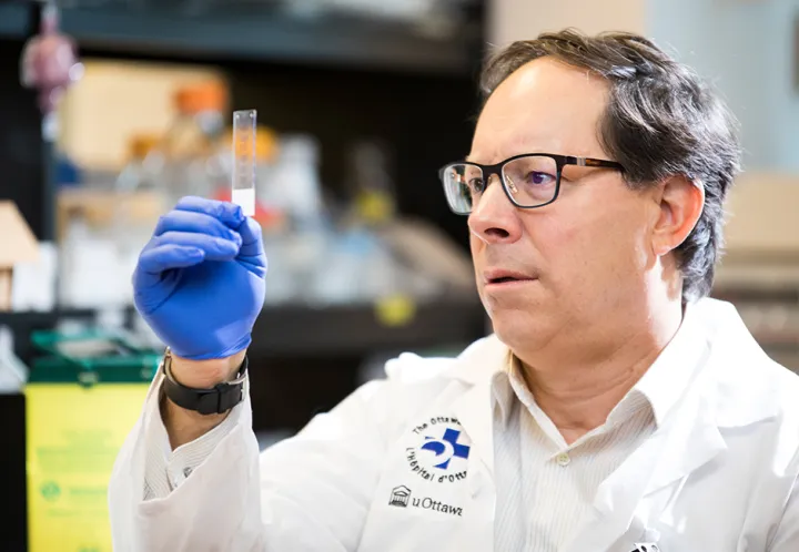 A man in a lab coat looks at a glass slide