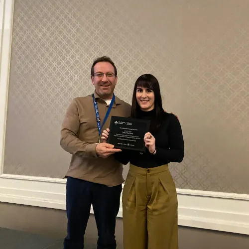 A man and a woman stand together holding an award