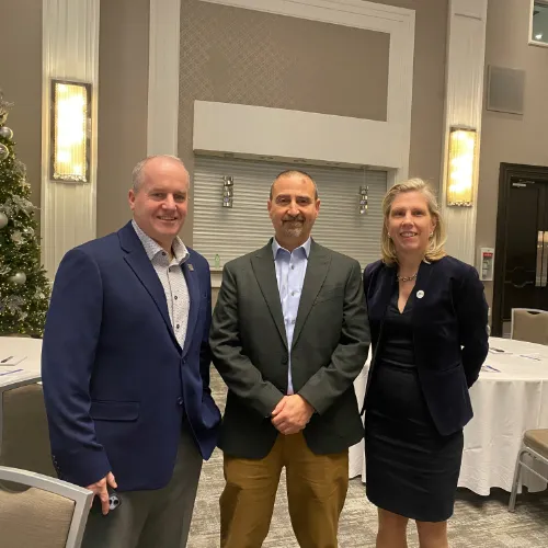 Two men and a woman stand and smile