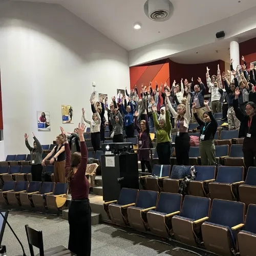A group of people in an auditorium stand and stretch