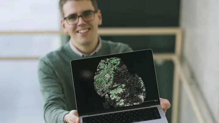 A man holds up a laptop showing a scientific image
