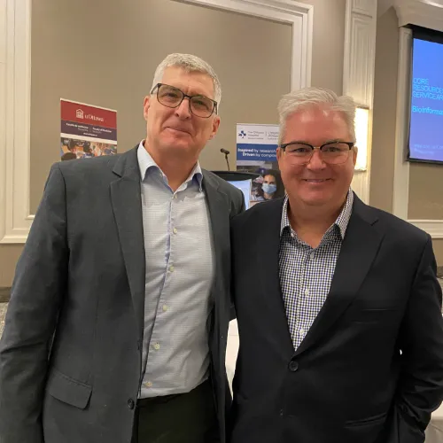 Two smiling men stand together