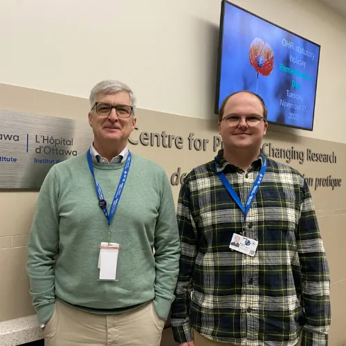 Two men stand and smile at the camera