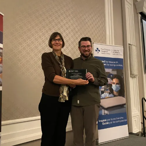A woman and a man stand together and hold an award