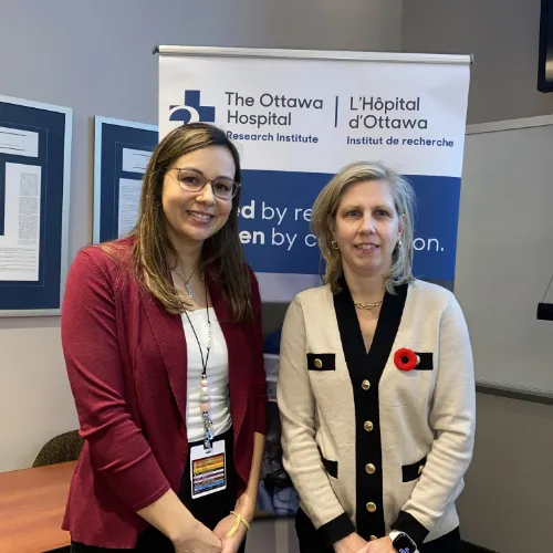 Two women stand in front of a pull-up banner