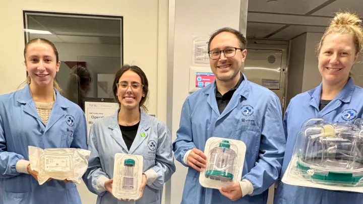 Four people wearing lab coats hold lab equipment