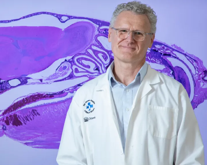 A man stands in front of an MRI image of a brain