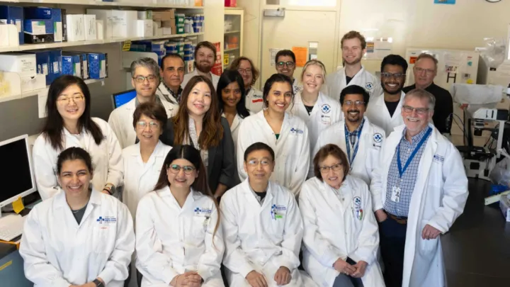 A group of people wearing lab coats stand together in a lab