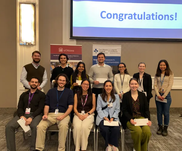A group of people (some standing and some sitting) hold awards 