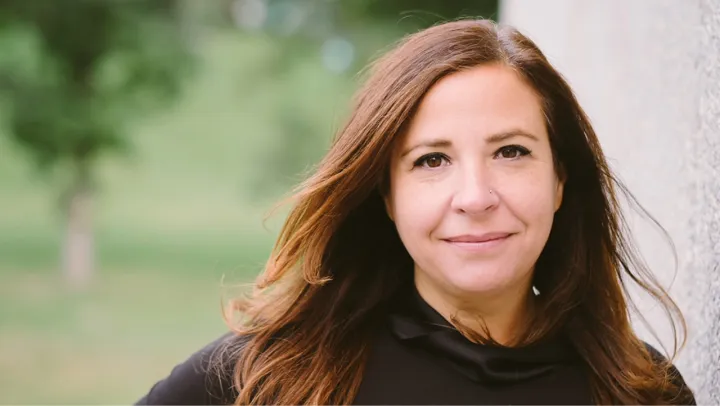 A woman standing outside smiles at the camera