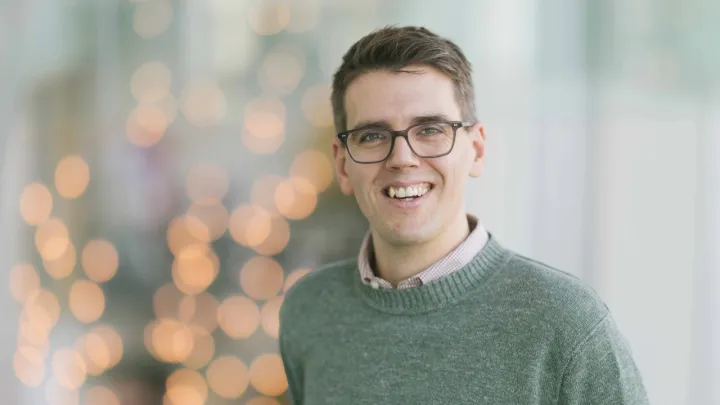 A man wearing glasses smiles at the camera