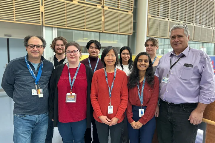 A group of people dressed casually pose for a photo in a hospital environment