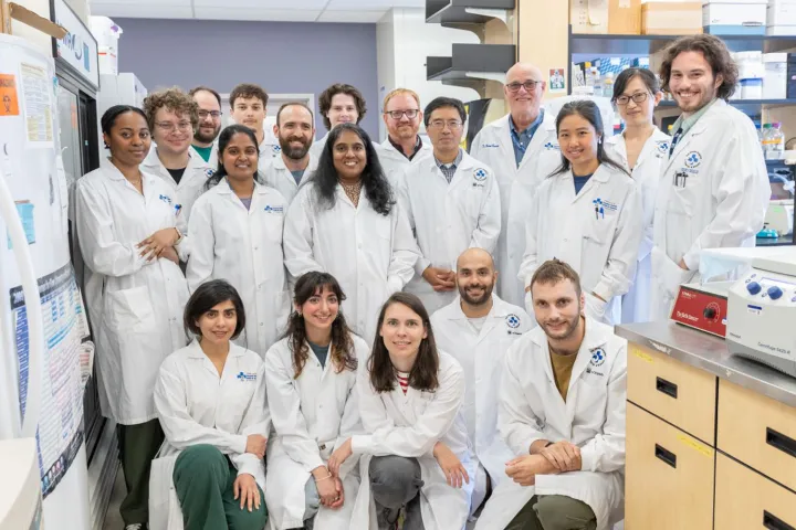 A group of people wearing lab coats pose for a photo in a lab