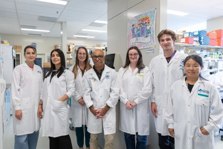 A group of people wearing lab coats pose for a photo in a lab