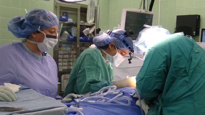 Trois prestataires de soins de santé en blouse effectuent une chirurgie