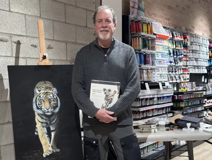 Man stands in art store next to painting of tiger