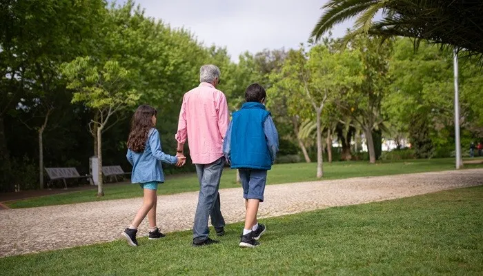 An older adult and two kids walking together outside