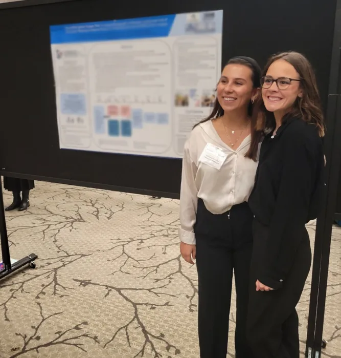 Two people stand near a poster