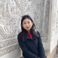 Portrait of a lady sitting with a designed wall as backdrop