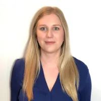A woman stands in front of a white wall