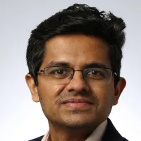 A man wearing glasses smile at the camera