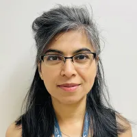 A woman wearing glasses smiles at the camera