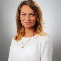 A woman wearing a white shirt smiles at the camera