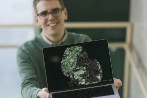 A man holds up a laptop showing a scientific image
