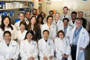 A group of people wearing lab coats stand together in a lab