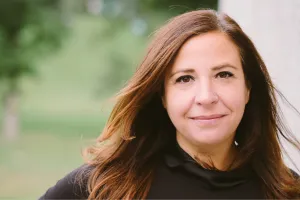 A woman standing outside smiles at the camera