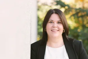 A woman stands outside and smiles at the camera