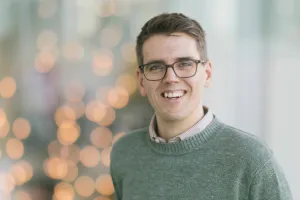 A man wearing glasses smiles at the camera