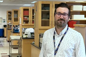 Man with glasses stands in front of a row of lab benches